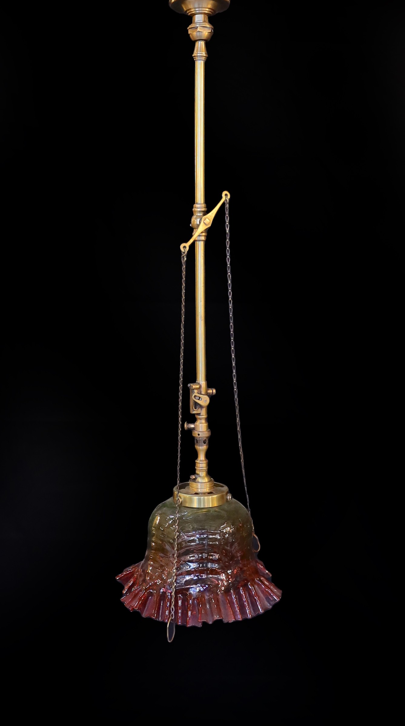 A 1920s English brass gasolier ceiling light with ruby tinted frilled glass shade, converted to electricity, height 76cm
